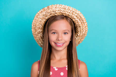 Photo of charming adorable little lady dressed dotted sarafan straw headwear smiling isolated teal color backgroundの写真素材