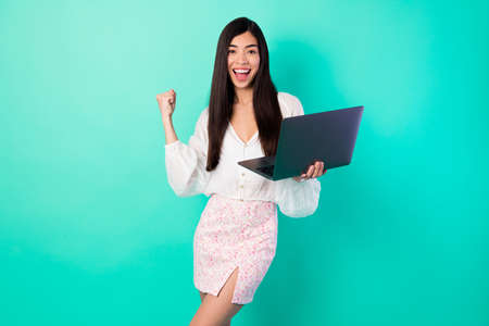 Photo of lady work remote netbook win partner deal fist up wear top shirt short skirt isolated cyan color backgroundの写真素材