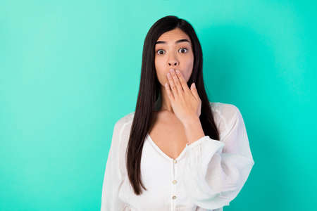 Portrait of impressed filipino lady arm cover mouth silent quiet isolated on vibrant aquamarine color backgroundの写真素材