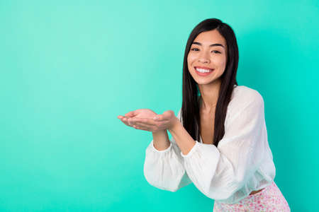 Portrait of adorable cheerful girl arms palms hold demonstrate empty space isolated on emerald color...