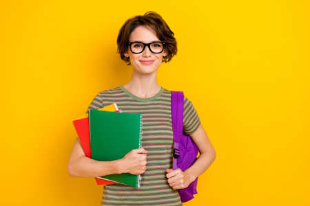 Photo of sweet cheerful girl dressed green t-shirt eyewear rucksack holding book isolated yellow...