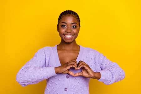 Photo of adorable cheerful girl arms fingers show heart gesture toothy smile isolated on yellow color backgroundの写真素材