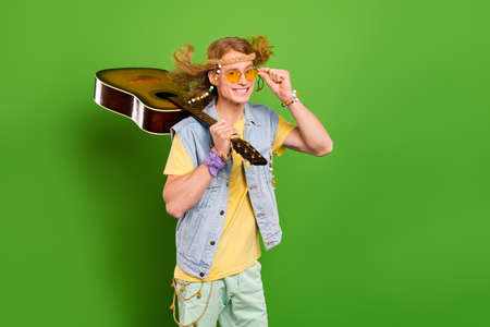 Photo of youngster guy wander musician hold guitar wear denim stylish jeans vest isolated bright color backgroundの写真素材