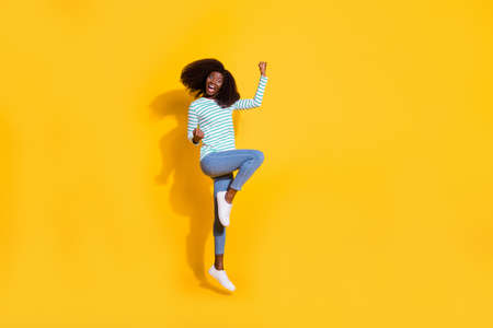 Full size photo of overjoyed satisfied person jumping raise fists celebrate luck isolated on yellow...