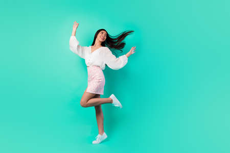 Full length photo of cheerful gorgeous girl dancing have good mood isolated on vivid turquoise color backgroundの写真素材