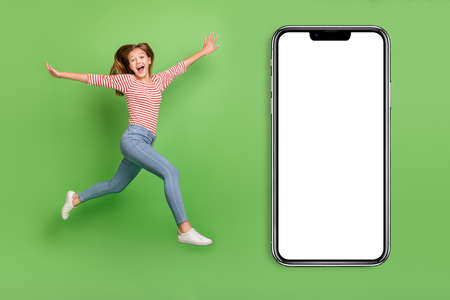 Photo of excited crazy inspired lady jump run have fun raise hands wear striped shirt isolated green...
