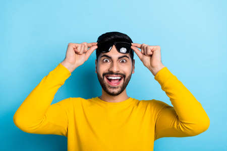 Photo of handsome impressed man wear yellow sweater arms dark glasses open mouth isolated blue color...