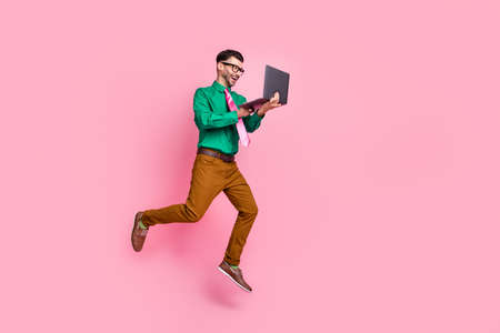 Full length photo of positive busy man dressed green shirt eyewear jumping typing modern device...