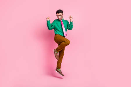 Full length photo of lucky pretty man dressed green shirt eyewear jumping rising fists isolated pink color backgroundの写真素材