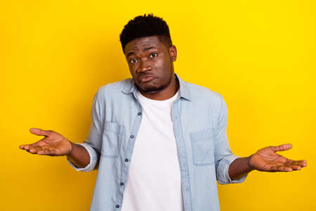 Photo of unknown millennial brunet guy shrug shoulders wear jeans shirt isolated on yellow color...