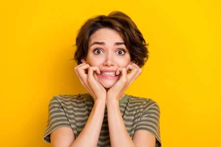 Photo of scared horrified lady wear striped t-shirt biting fingers isolated yellow color backgroundの写真素材