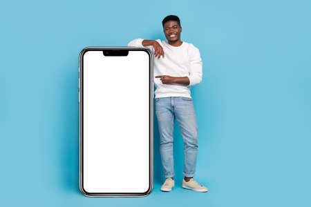 Full body portrait of cheerful person indicate finger empty space promo blank isolated on blue color backgroundの写真素材