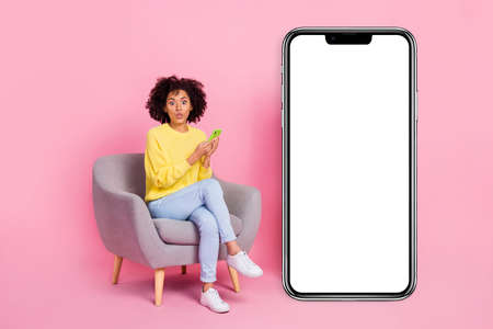 Full body photo of young girl impressed sit lounger use cellphone comment post isolated over pink color backgroundの写真素材