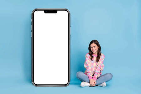 Full length photo of young pretty girl sit floor promoter advertise isolated over blue color backgroundの写真素材