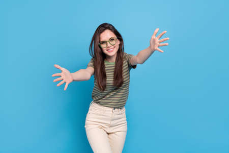 Photo of impressed millennial brunette lady hug you wear eyewear green t-shirt isolated on blue backgroundの写真素材