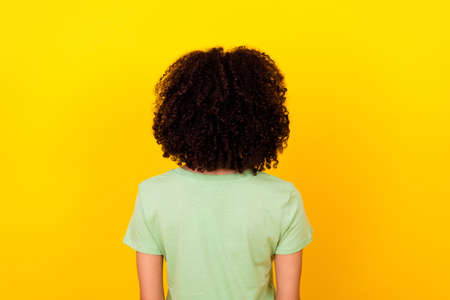 Photo of charming curly lady wear green t-shirt standing back showing hairdo isolated yellow color backgroundの写真素材
