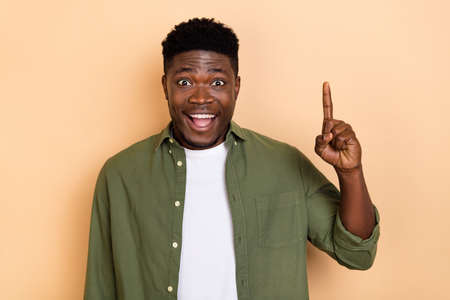 Photo of cute millennial brunet guy index up wear khaki cloth isolated on beige color backgroundの写真素材