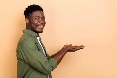 Profile photo of nice millennial brunet guy hold empty space wear khaki shirt isolated on beige color backgroundの写真素材