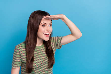 Photo of cute millennial brunette lady look empty space wear striped t-shirt isolated on blue color backgroundの写真素材