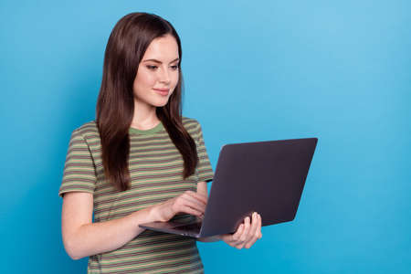 Photo of ceo young brunette lady type laptop wear striped t-shirt isolated on blue color backgroundの写真素材