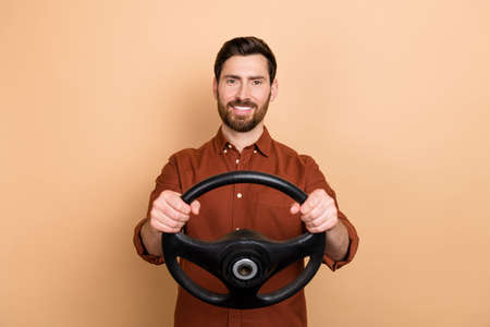 Photo of cheerful satisfied man hands hold wheel toothy beaming smile isolated on beige color backgroundの写真素材