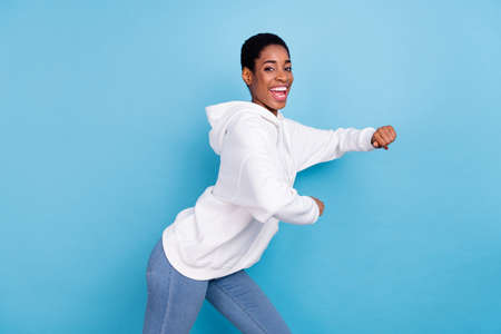 Photo of excited beautiful trans girl wear white sweatshirt dancing isolated blue color background