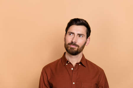 Photo of minded positive person look interested empty space contemplate isolated on beige color backgroundの写真素材