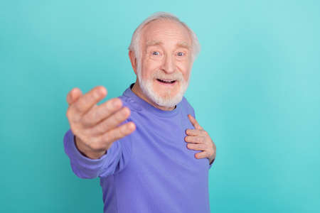 Portrait of cheerful satisfied aged man arm touch chest invite welcome you isolated on aquamarine color backgroundの写真素材