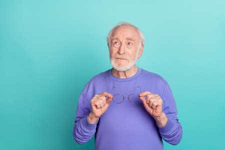 Portrait of focused minded granddad arms hold glasses look interested empty space isolated on teal color backgroundの写真素材