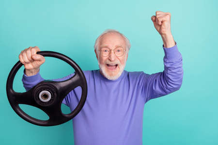 Portrait of delighted overjoyed person hold wheel raise fist celebrate isolated on aquamarine color backgroundの写真素材