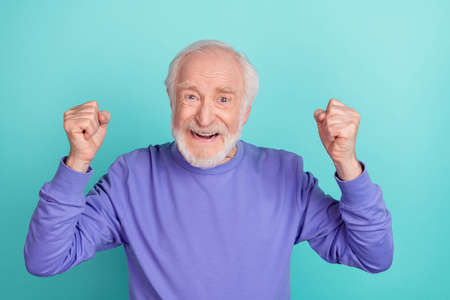 Portrait of delighted astonished person raise fists shout yes success isolated on cyan color backgroundの写真素材