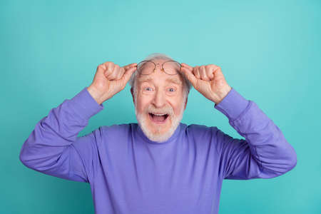 Portrait of excited funky granddad hands touch glasses open mouth unbelievable isolated on cyan color backgroundの写真素材