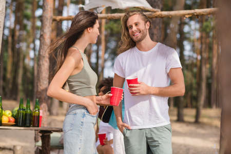 Photo of peaceful cheerful people hold plastic beer cups communicate enjoy sand beach party outdoorsの写真素材