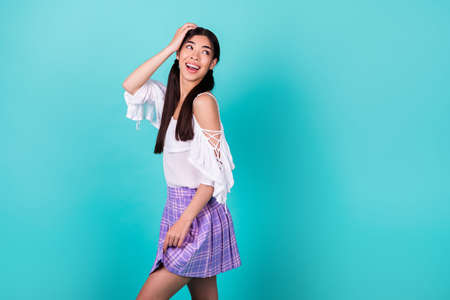 Full length profile portrait of cheerful nice lady arm touch head look empty space isolated on turquoise color backgroundの写真素材