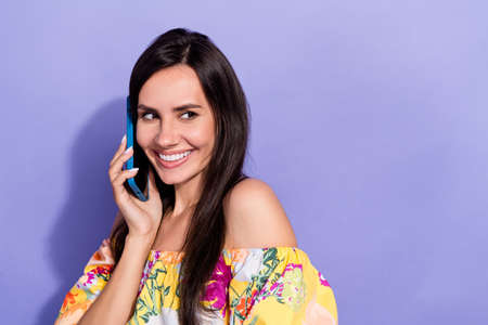 Portrait of gorgeous positive lady speak telephone toothy smile look empty space isolated on purple color backgroundの写真素材