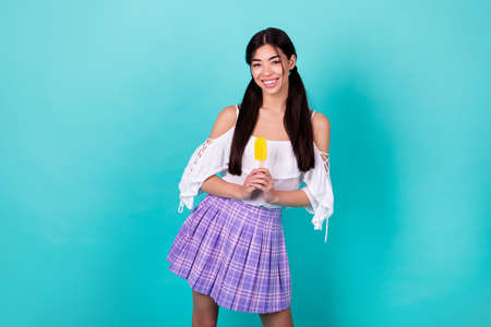 Photo of attractive college lady holding fruit popsicle season refreshment isolated cyan color backgroundの写真素材