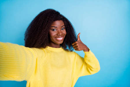 Photo of attractive girl wear stylish clothes show approve symbol enjoy quality yellow pullover isolated on blue color backgroundの写真素材