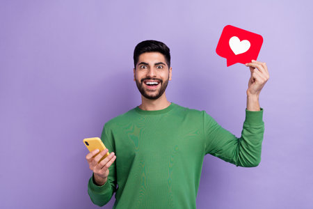 Photo of handsome cheerful positive brunet hair guy wear green long sleeve hold smartphone got like...
