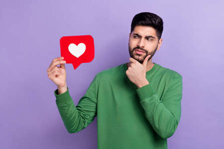 Photo of stylish young handsome guy dressed green long sleeve hand on chin look at like suspiciously...