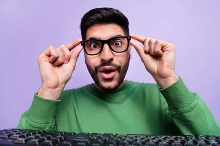 Photo of impressed excited handsome geek man dressed green pullover hands touch glasses staring...