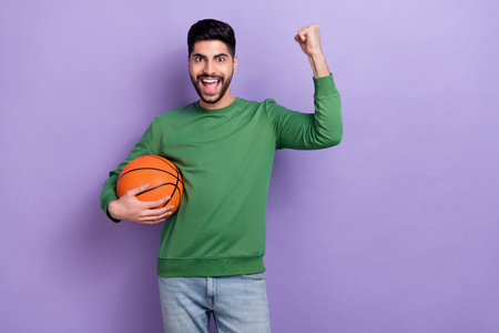 Photo portrait of sporty young latin man basketball fan scream yeah raise fist wear stylish green look isolated on purple color backgroundの写真素材