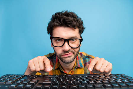 Photo of unhappy brunet guy type keyboard wear eyewear plaid shirt isolated on blue color background