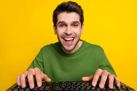 Photo of shocked funny guy dressed green pullover typing modern device isolated yellow color...