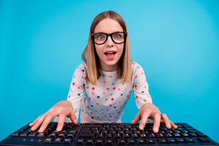 Photo of funny funky small girl wear dotted shirt eyeglasses typing modern device isolated blue color backgroundの写真素材