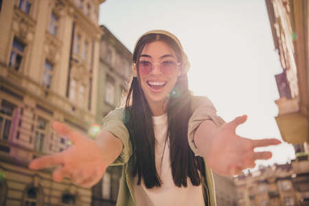 Photo of cheerful adorable girl raise arms camera you invite cuddle toothy smile free time outdoorsの写真素材