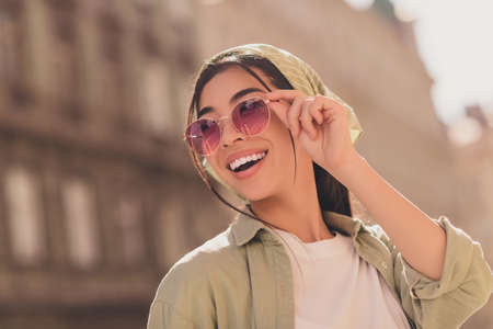 Portrait of adorable positive person toothy smile arm touch sunglass have good mood city center outsideの写真素材