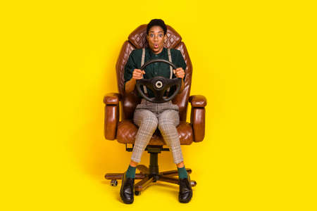 Portrait of attractive funny amazed woman holding steering wheel riding wow isolated over bright yellow color backgroundの写真素材