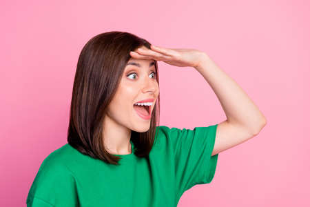 Closeup photo of young attractive shocked woman wear green t-shirt looking far away isolated on pink...