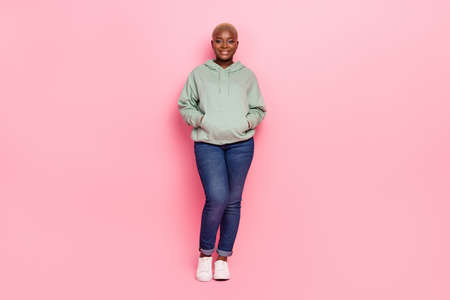 Full length photo of fashionable confident female wearing jeans and comfy hoodie isolated on pink...