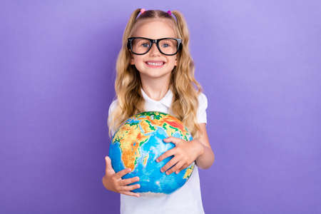 Photo of charming small girl tails eyewear hug globe earth school shopping dressed stylish white look isolated on violet color backgroundの写真素材